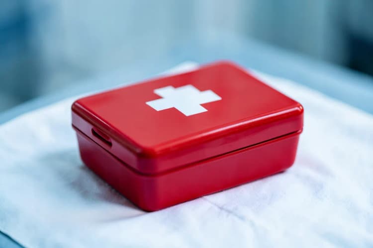 Seção 5: Um kit de primeiros socorros vermelho fechado sobre um pano branco.