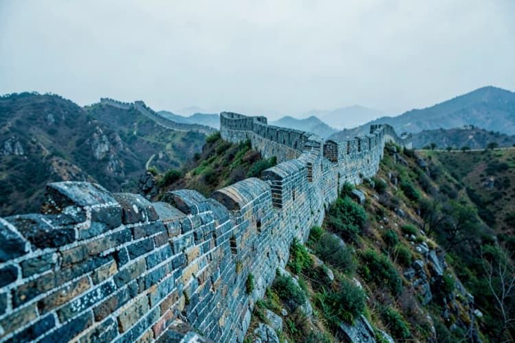 A Grande Muralha da China, com montanhas ao fundo.