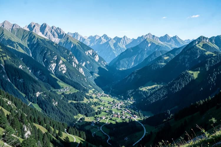 Uma paisagem montanhosa com uma pequena vila pitoresca aninhada no vale, sob um céu claro.